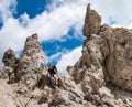 Young woman summerÃÂ hiker with backpack climbing with help of metal cables, iron rungs, pegs, and steps on huge limestone rock
